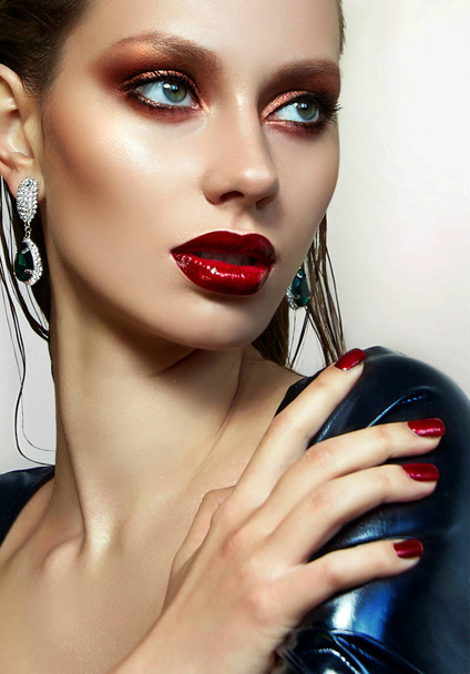 Girl in latex dress. Red lipstick and red nail polish. Beautiful and effective young girl with bright make-up and wet hair. The shadows are metallic. Fashion, beauty, advertising. - Φωτογραφία, εικόνα