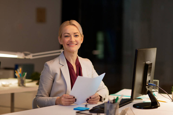 businesswoman with papers working at night office - Foto, Bild