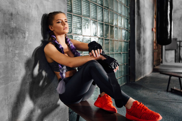 Fitness girl relaxing sitting on sports school bench after a hard boxing training. - Fotoğraf, Görsel