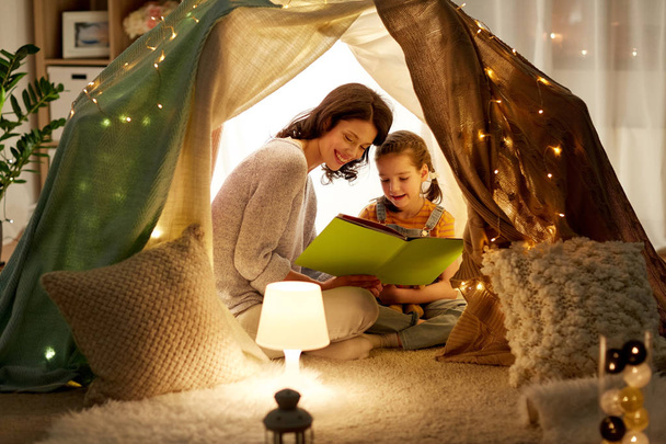 happy family reading book in kids tent at home - 写真・画像