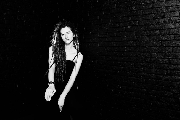 Studio shoot of girl in black on chair with dreads on brick back - Zdjęcie, obraz