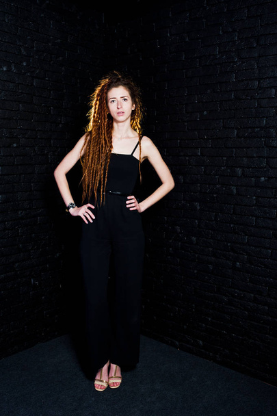 Studio shoot of girl in black with dreads on brick background. - Foto, afbeelding