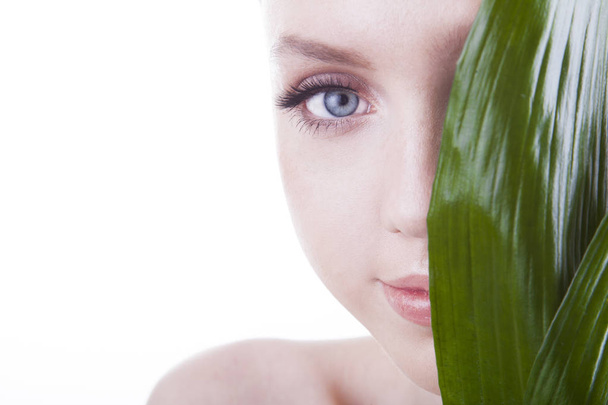 Beauty shoot. European, young, blue-eyed woman posing with fresh, green leaf. - Photo, Image