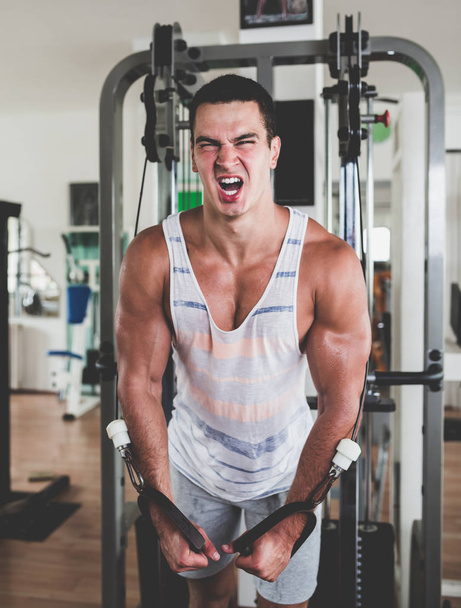 Young attractive adult man exercising and doing weight lifting at fitness gym. Sport training indoors - Foto, imagen