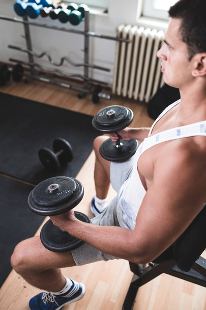 Young attractive adult man exercising and doing weight lifting at fitness gym. Sport training indoors - Foto, Imagem