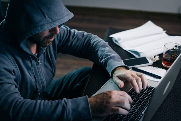 An experienced hacker working on a laptop at home - Foto, Bild