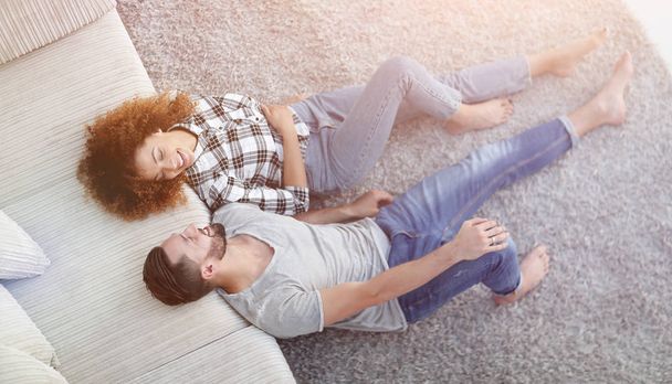 smiling couple lying on a carpet in a new apartment - Φωτογραφία, εικόνα