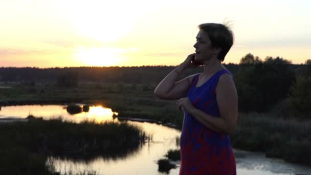 Dreaming kobieta grzebienie jej włosy na brzegu jeziora - Materiał filmowy, wideo