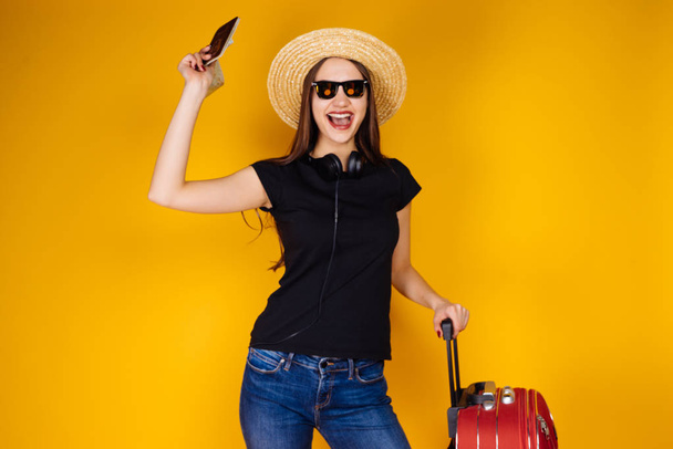 happy tourist woman stands next to a red suitcase, and holds a passport - Fotoğraf, Görsel