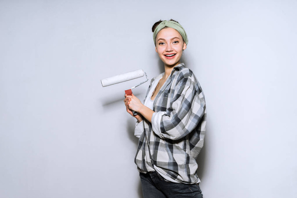 woman on a gray background preparing to paint a wall - Fotó, kép