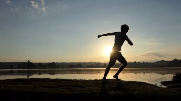 Νεαρός χορεύει ντίσκο σε μια τράπεζα στη λίμνη το καλοκαίρι - Πλάνα, βίντεο