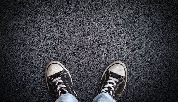 Adolescente usando zapatos de lona en el fondo de asfalto con espacio de copia
 - Foto, imagen