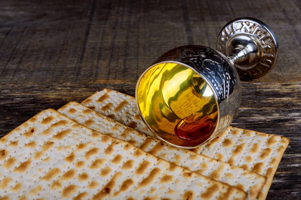 Κρασί και matzah closeup γυαλί του Πάσχα. Φωτιζόμενο θολή matzah υφή στο παρασκήνιο. - Φωτογραφία, εικόνα