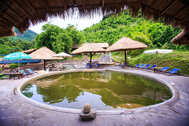 closeup round hot water pool to bathe against plants folding chairs reed umbrellas in tropical park in Vietnam - Photo, Image