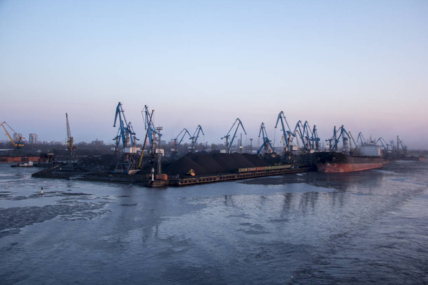 Szállítás a tengeri konténerek, és a gáz olaj tartályok a dokkok. import export-és üzleti logisztikai. Teherszállító hajó dokkolt a kikötőben. Rakomány daru téli estére, a Port-Riga, Lettország. - Fotó, kép