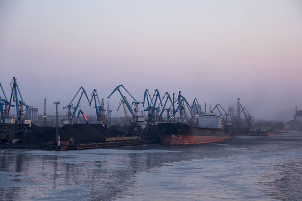 Szállítás a tengeri konténerek, és a gáz olaj tartályok a dokkok. import export-és üzleti logisztikai. Teherszállító hajó dokkolt a kikötőben. Rakomány daru téli estére, a Port-Riga, Lettország. - Fotó, kép