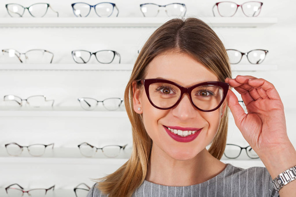 Young woman choosing eyeglass frame - Foto, Imagen