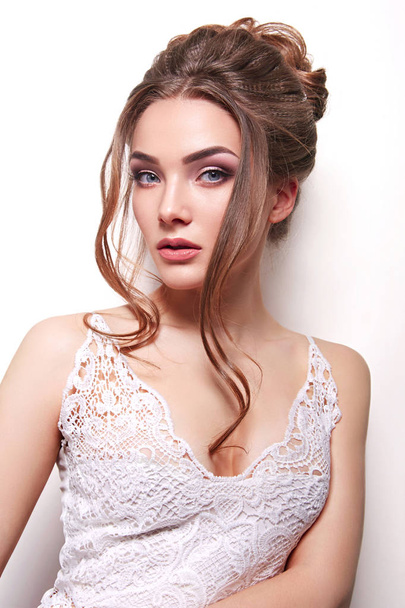 Young beautiful tender girl bride in studio on white background. Close-up. High festive hairstyle. Natural makeup. Wedding. Cosmetics, beauty salon, fashion. Smooth healthy skin, highlighter.Wedding. - Φωτογραφία, εικόνα