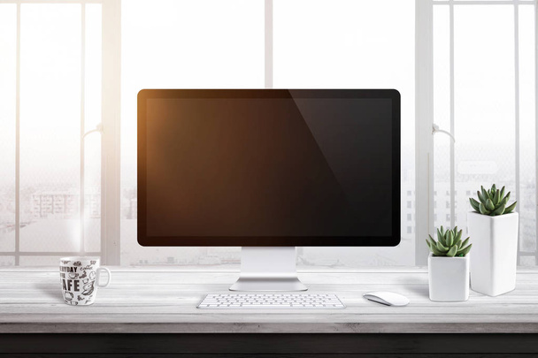 Computer display met leeg scherm voor mockup op kantoor of werk kamer. Venster en zon licht in de achtergrond. Kopje koffie en twee planten naast. - Foto, afbeelding