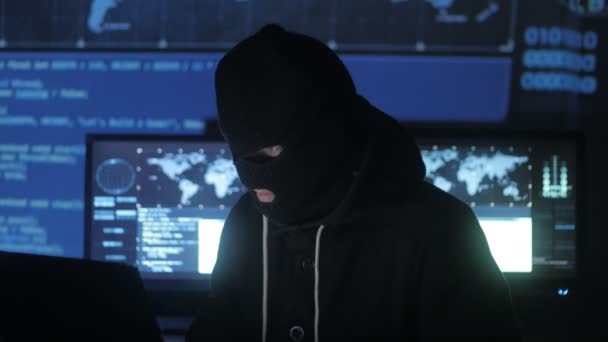 マスクで危険なハッカーは、セキュリティ パスワードを見つけるコードと番号を使用してシステムを入力しようとします。サイバー犯罪の概念. - 映像、動画