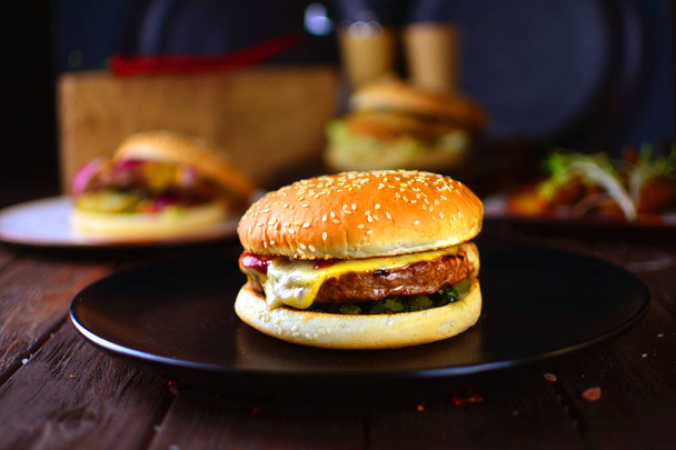 Macro of a traditional American hamburger dish with a tasty big steak. Horizontal orientation. Burger on a black plate. - Foto, imagen