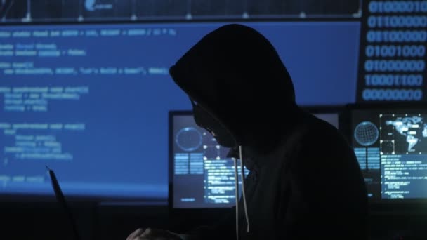 Anonieme hacker in het masker probeert in te voeren van het systeem met behulp van codes en nummers om uit het beveiligingswachtwoord te vinden. Het concept van cybercriminaliteit. - Video