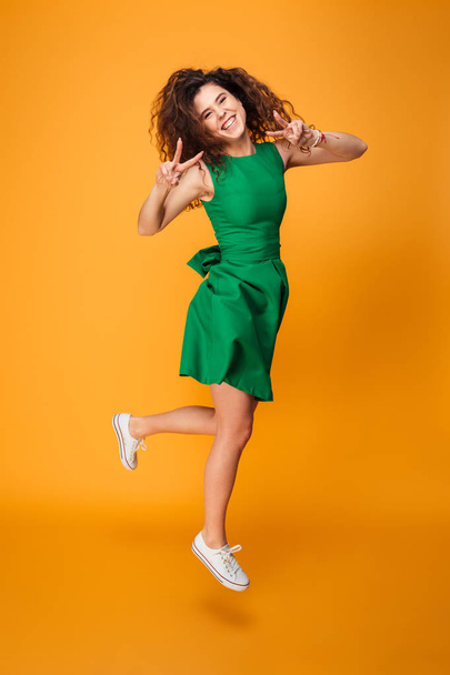 Full length portrait of an excited curly haired girl jumping - Fotoğraf, Görsel