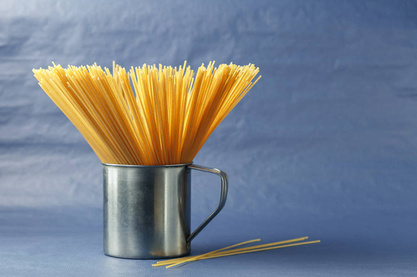 Ongekookte pasta spaghetti op een paarse achtergrond - Foto, afbeelding