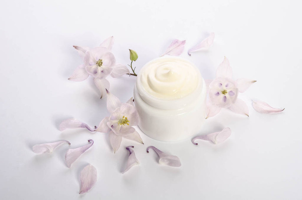 Cute flowers and petal and a jar of natural body cream - Foto, afbeelding