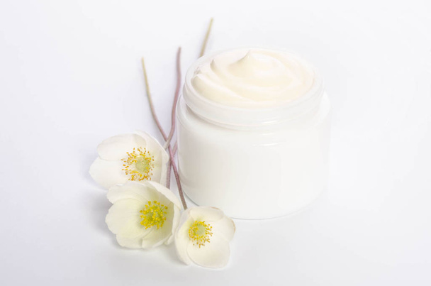 Cute flowers and a jar of natural body cream isolated on white - 写真・画像
