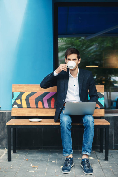Genç yakışıklı adam zevk kahve çalışma üstünde laptop - Fotoğraf, Görsel