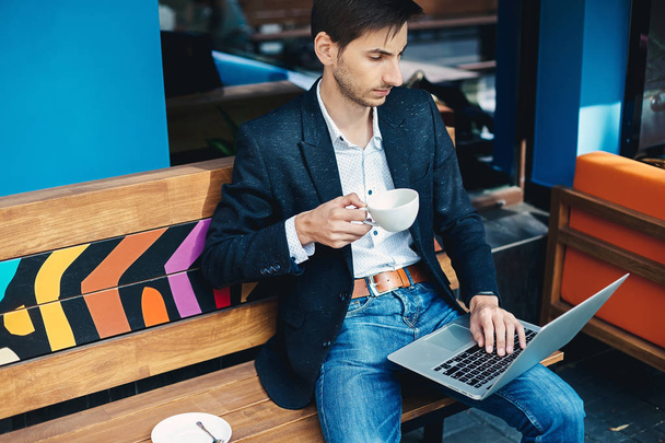 Young handsome man enjoy coffee working on laptop - Fotó, kép