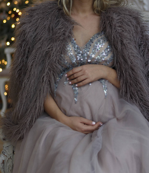pregnant girl sits on the couch in a blue dress with sparkles in - Foto, Bild