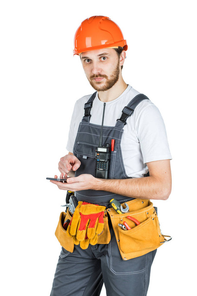 The man builder records something in the phone. Repair and construction. Isolated over white background - Photo, Image