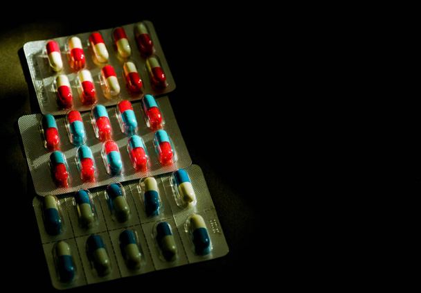 Värikäs antibiootti kapseli pillereitä läpipainopakkauksessa tumma bac
 - Valokuva, kuva