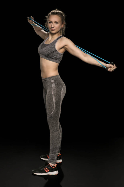 athletic girl stretches and exercises with a flexible rope - Foto, Imagem