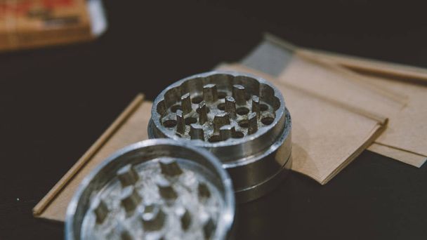 Moedor de prata metálico para botões de deitado no close-up papéis de fumaça de maconha. Legalizar o conceito  - Foto, Imagem