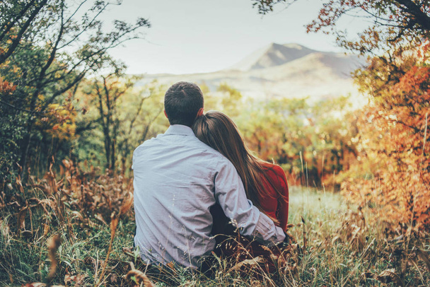 pareja está abrazando y sentado cerca en el bosque
  - Foto, imagen
