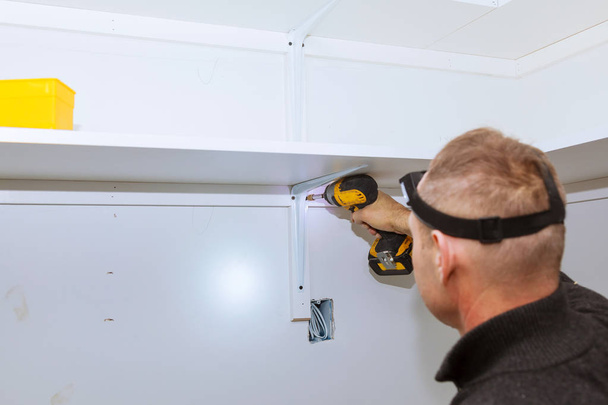 Profile view of a good looking handyman making some drill wall installing a shelf - Фото, зображення