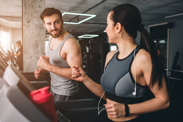 Nice picture of two cheerful people hacving the same workout on the running machine. Besides working they are talking with each other, smiling and having fun. - Fotoğraf, Görsel