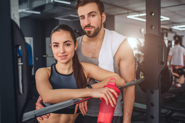 Fantastic couple is standing together in the training room and posing on camera. They look good together. This couple is having some rest after hard workout. - Фото, зображення