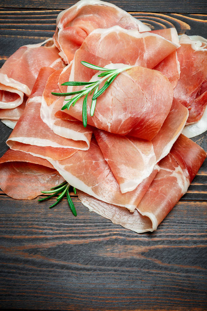 Italian prosciutto crudo or spanish jamon. Raw ham on wooden background - Foto, Bild