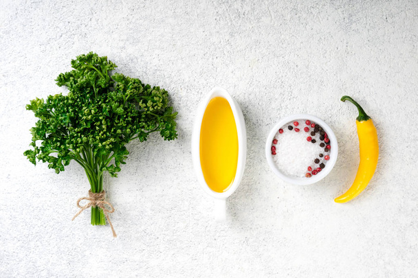 Kräuter und Gewürze Hintergrund. Gewürze frische Petersilie, Salz, Pfeffer, Olivenöl und gelbe Chilischote auf weißem Betongrund. vegetarische Ernährung Hintergrund - Foto, Bild
