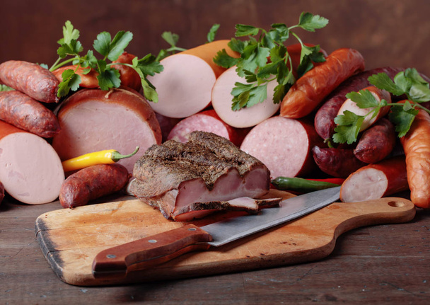 Различные сосиски и копченое мясо на деревянном столе
 . - Фото, изображение