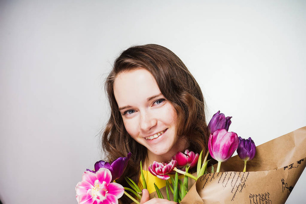 happy young girl holding a bouquet of fragrant flowers, smiling, celebrating a world women's day - Fotó, kép