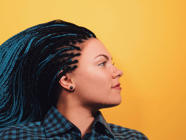 Beautiful young girl with african blue braids. Woman on bright yellow background. Dyed Hair moves. Hipster. - Фото, зображення