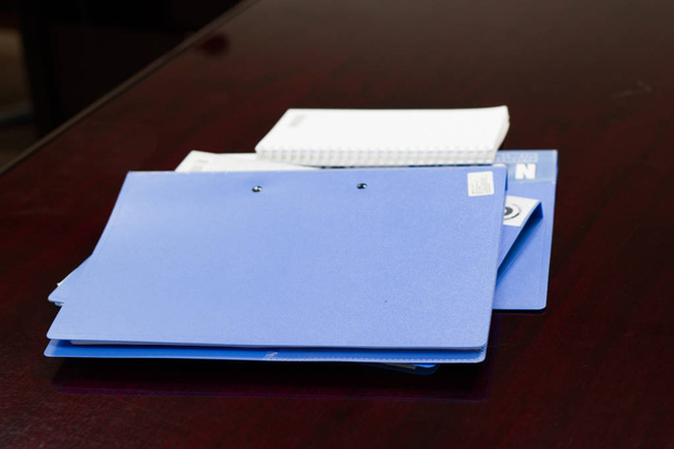 arquivos azuis pasta retenção de contratos e vidro na mesa marrom na sala de conferências
 - Foto, Imagem