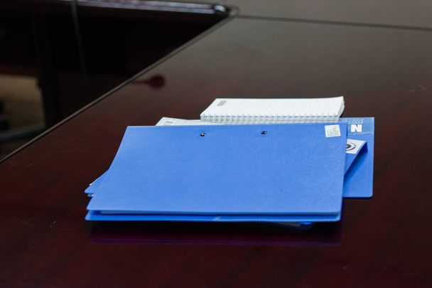 会議室の茶色の机の上の契約とガラスの青いファイルフォルダの保持 - 写真・画像