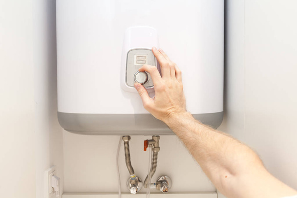 Close-up van man handen vaststelling van de temperatuur van het water in elektrische Boiler - Foto, afbeelding