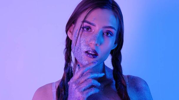 Portrét krásné ženy s jiskří na její tvář v ultrafialovém světle. Dívka s Art Make-Up v růžové a modré. Modelka s barevný make-up - Fotografie, Obrázek